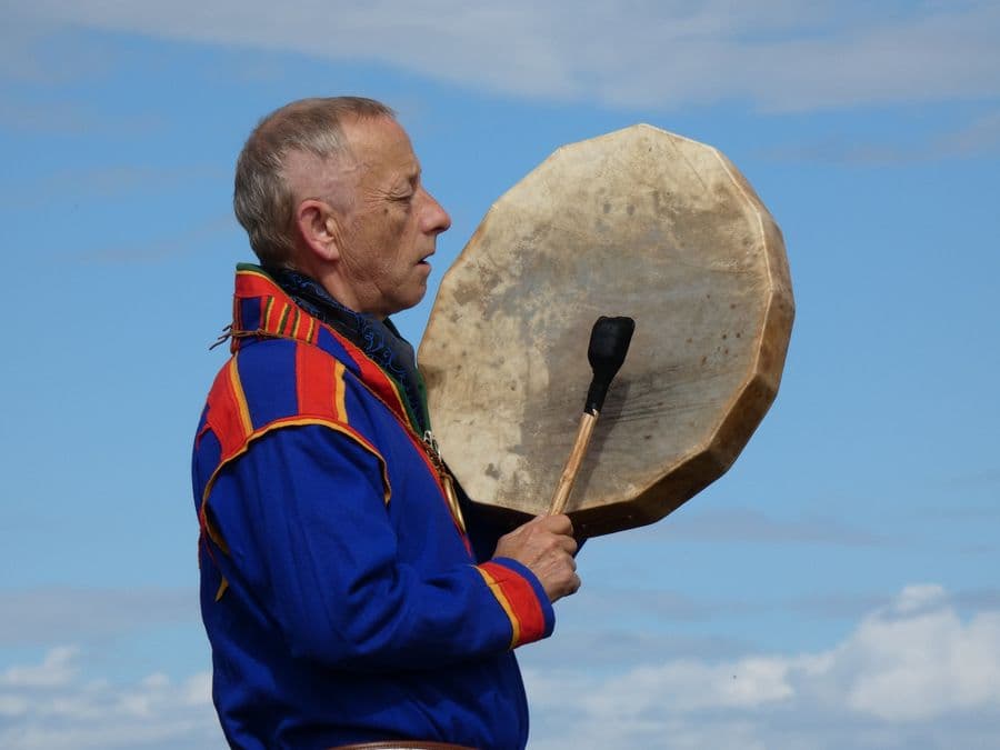 The Sámi shaman with his frame drum, mid-song against the sky