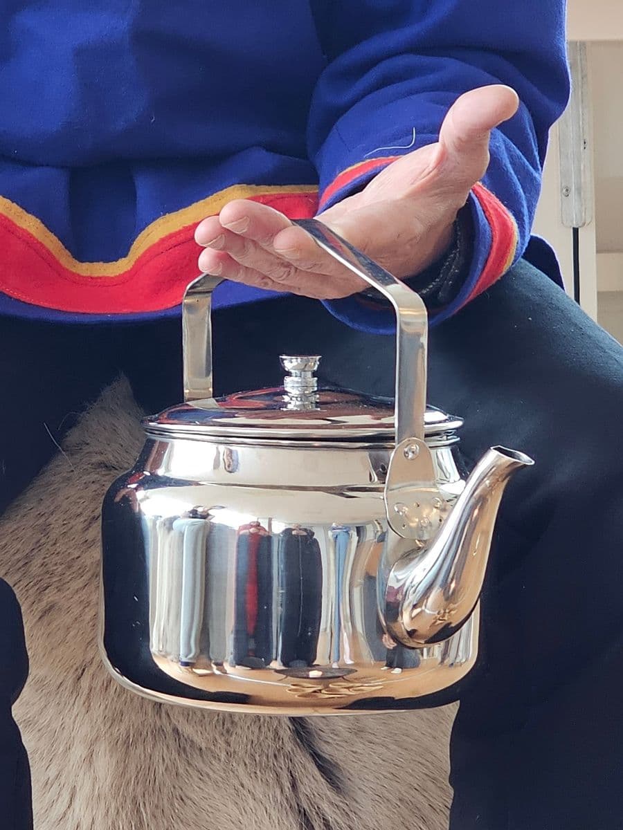 A hand held over the coffee kettle — the blessing that opens the Sámi coffee ceremony