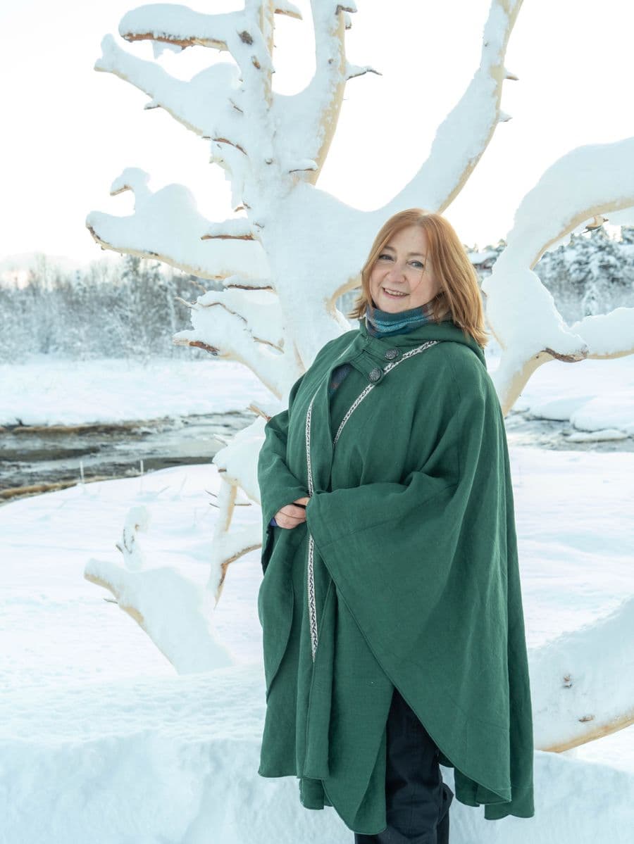 Ekaterina Trunova, founder and director of Troll Museum Tromsø, in a green cape in a snowy winter landscape